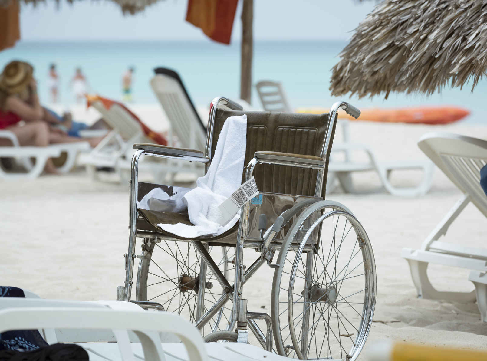 Disabled holiday directory - Closeup view of empty wheelchair standing on tropical beach against ocean background